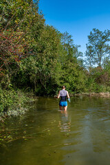 Young Woman Walks On Flooded Path Through Forest At High Water In Danube Wetlands National Park In Austria