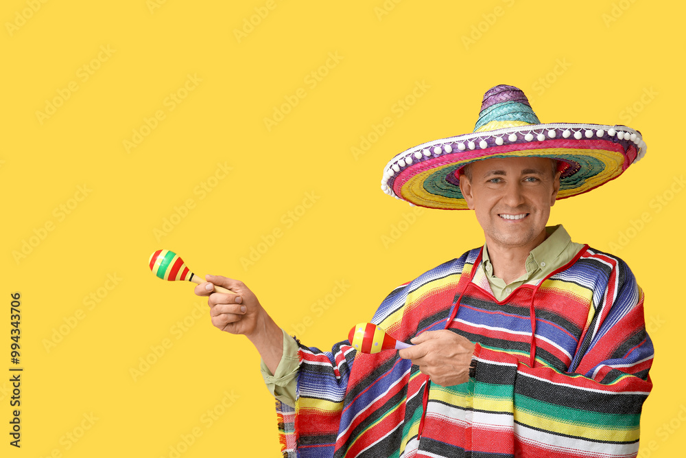 Wall mural Handsome mature Mexican man in sombrero hat with maracas on yellow background