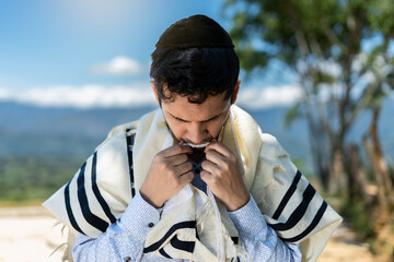 Young Jewish Man Kissing the Two Front Tzitzit of His Tallit During Shema Israel in Shacharit Prayer