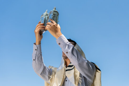 Young Jewish Man Raising a Sefer Torah to the Sky in Celebration of Simchat Torah