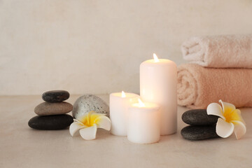 Composition with burning candles, spa stones and flowers on light background