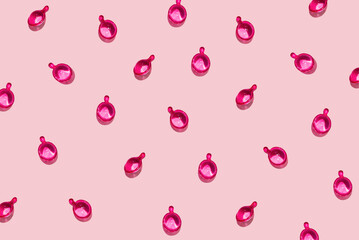 Pattern of pink cosmetic capsules for face or hair care on pastel pink background. Creative concept of beauty products