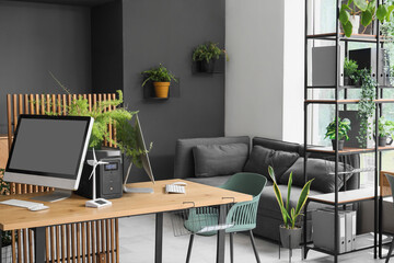 Interior of engineer's office with desk, wind turbine model and plants