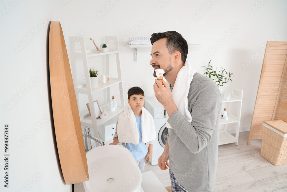 Poster Happy father and his little son holding brush with towels in bathroom