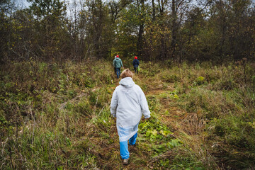 A group of enthusiastic explorers is joyfully trekking through a vibrant and dense forest trail,...