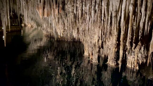 Background. Inside the cave. Underwater reservoir. Camera movement, bizarre and beautiful stalactites and stalagmites. Reflection of these stone structures in the water of the underground reservoir 02