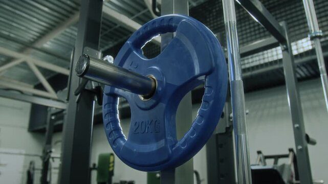 Close up view of twenty kilo weight plate hanging on storage rack in gym equipped with exercise machines