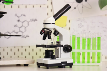 Modern microscope and chemical flasks on table against mood board in teenager's room