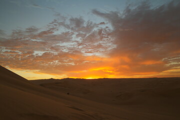 Stunning sunset over the Huacachina desert in Peru, illuminating the sky with vibrant colors after a day of exploration and adventure