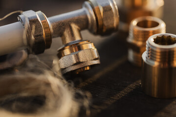 Brass plumbing fittings and PEX pipe fittings lying on an old wooden countertop, next to a tool, plumbing wrenches (selective focus)