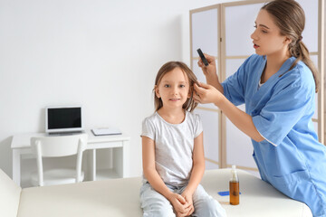 Female doctor with magnifier checking little girl's head for pediculosis in clinic