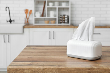 Holder with paper tissues on wooden table in kitchen