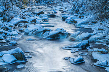 Winter Vydra river and stones under the snow, Sumava national park, Czech republic