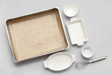 Composition with baking tray, whisk and dishes on grey background