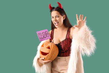 Young woman with Halloween pumpkin on green background