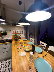 Table served for Christmas dinner in living room. Christmas tree background. Winter holidays