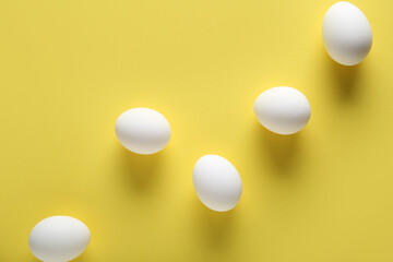 Raw chicken eggs on yellow background