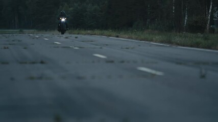 Man in black helmet rides motorcycle along secondary road near highway with heavy traffic of cars and trucks. Motorcycles, especially electric ones, are cleaner vehicles than cars