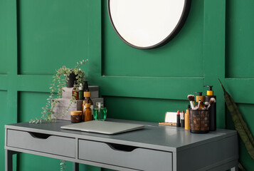 Laptop with makeup products and plant on table in room