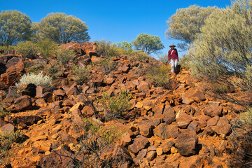 Woman descending a red stoney hill in the remote, arid outback of the mid west of Western...