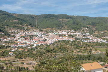 Vista panorâmica da Serra da Estrela, com seus imponentes picos rochosos, vastos campos verdes e céu claro, oferecendo uma paisagem tranquila e natural da maior montanha de Portugal.