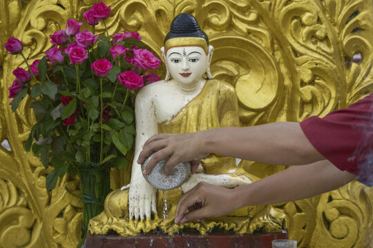 Anonymous buddhist water pouring ritual at Mount Popa Buddha statue