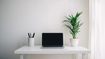Minimalist workspace with laptop, potted green plant, and pen holder on a white desk in a bright, airy room. Copy space