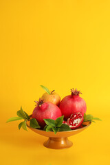 Pomegranates and apples in a vase on Yellow background. Rosh Hashanah (jewish holiday) concept.