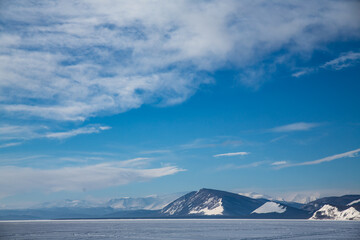 A snowy mountain looms against a blue sky filled with clouds