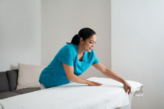 Female therapist preparing massage table for client