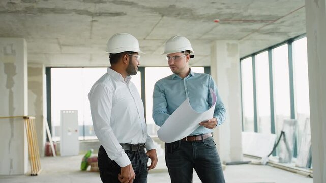 Two diverse civil engineers reviewing construction site blueprint