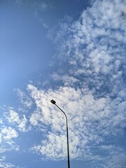 a street lighting pole against a cloudy blue sky