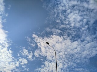 a street lighting pole against a cloudy blue sky