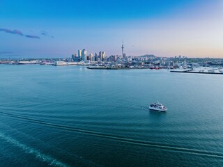 Ferry on the Waitemata Harbour at sunset. In the background is downtown Auckland, Auckland, New...