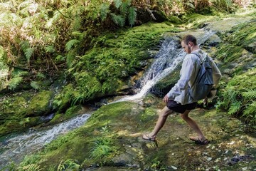Fototapeta premium Small waterfall and man on The Pinnacles bush walk hiking trail in the Kauaeranga Valley, Coromandel Peninsula, Waikato, New Zealand.