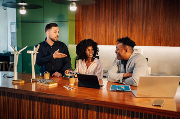 Interracial ecology experts discussing sustainability at office.