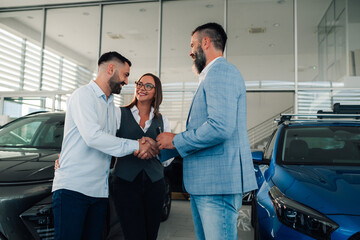 Happy couple finalizes deal with dealership expert in showroom