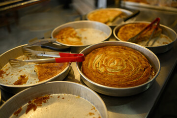 Freshly baked pies in aluminum pans with serving tongs on the table