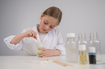 Caucasian girl doing chemical experiments on a white background. Making slime.