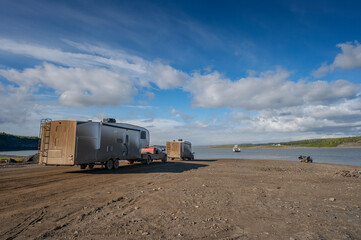 Fototapeta premium Mud covered motor homes wait for the Mackenzie River ferry crossing on the Dempster Highway