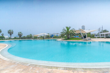 amplia piscina con toldos y  palmeras