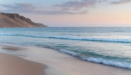 Obraz premium Peaceful ocean sunset beach with blue and orange sky with water lapping on the sand