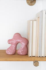 Pink Abstract Ceramic On Wooden Shelf With Books