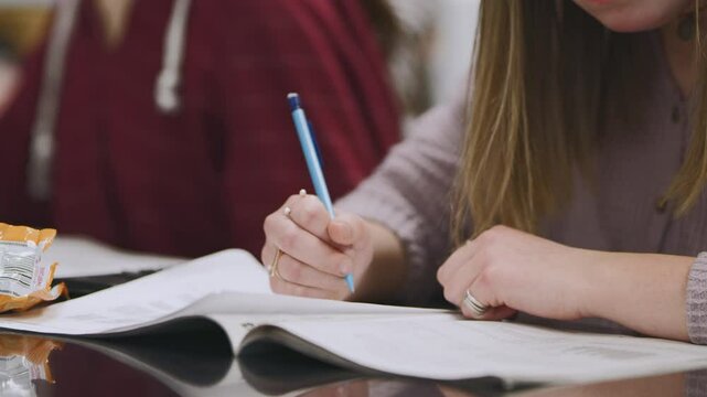 Student enjoys snack while completing workbook during class activity