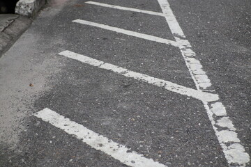 The photo shows a street with diagonal white parking lines and a sidewalk on the left.