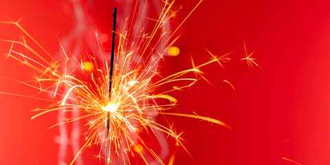 Beautiful glowing sparklers on colored background. Colorful sparklers sparkling against vibrant red bokeh background, creating festive and celebratory atmosphere. Christmas mood, festive red backgroun