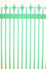 A green metal fence with decorative finials on top.