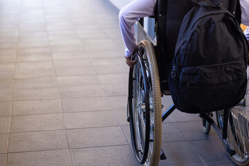 Navigating school hallway, african american girl in wheelchair with backpack, moving forward