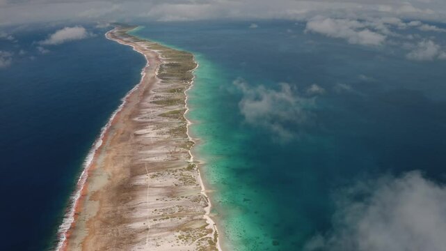 Overhead perspective of Rangiroa, largest atoll in Tuamotus archipelago, stunning turquoise lagoon and vibrant coral reefs. High angle over the clouds flight. Remote wild nature exotic summer travel.