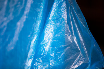 Blue plastic bag on black background. Close-up of plastic bag.